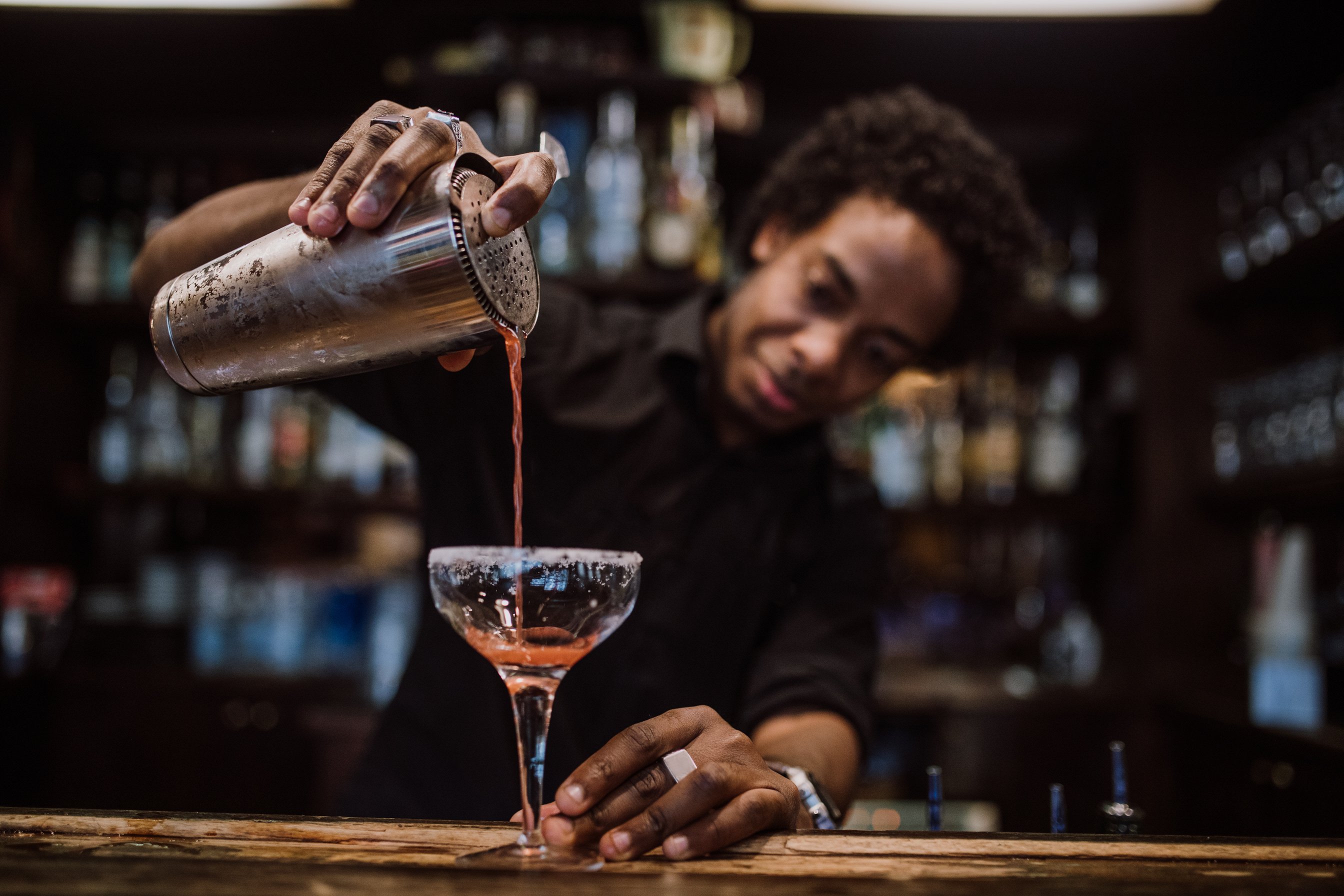 Young bartender pouring cocktails in a cocktail bar