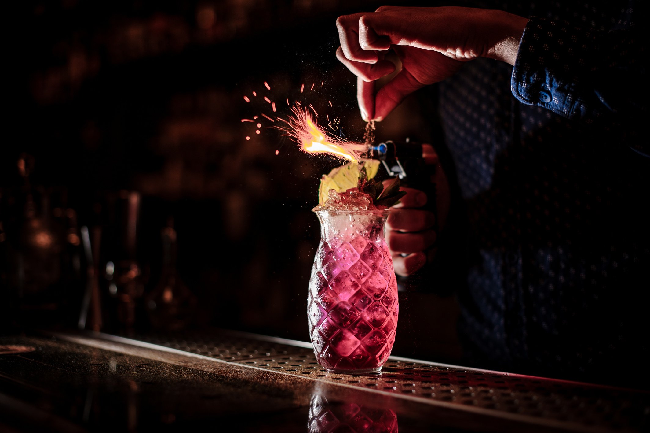 Bartender making a sweet and fresh strawberry mojito summer cocktail with a smoke note on the dark background